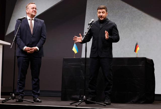 German Defence Minister Boris Pistorius (L) listens as Ukrainian President Volodymyr Zelensky addresses journalists during their visit at the production facility of drone producing company Quantum Frontline Industries (QFI) in Gilching near Munich, southern Germany, on the sidelines of the 62nd Munich Security Conference (MSC) on February 13, 2026. Heads of state and government as well as foreign and defence ministers from all over the world are expected to attend the security policy talks from February 13 to 15, 2026. (Photo by Alexandra BEIER / AFP)