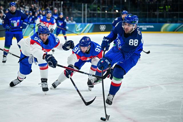 Italy's #88 Tommaso De Luca (R) controls the puck past Slovakia's #52 Martin Marincin (L) and Slovakia's #91 Matus Sukel (rear C) during the men's preliminary round Group B Ice Hockey match between Italy and Slovakia at the Milano Rho Ice Hockey Arena at the Milano Cortina 2026 Winter Olympic Games in Milan, on February 13, 2026. (Photo by JULIEN DE ROSA / AFP)