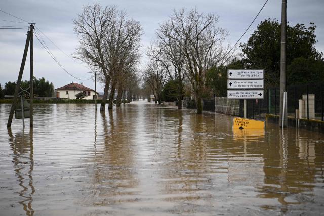This photograph shows the overflowing Garonne river inundating a road in Tonneins, south-western France on February 13, 2026, after winds of Storm Nils swept across France. Storm Nils, which swept across France for two days, has claimed a second life according to the government in the south-west, where a red alert remains in place for flooding on the Garonne river. France's government spokesperson announced on the morning of February 13, 2026, on French TV channel TF1 the death of a man who was "on a ladder in his garden" in Tarn-et-Garonne. (Photo by Christophe ARCHAMBAULT / AFP)