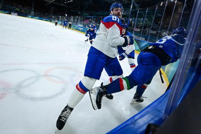 Slovakia's #81 Erik Cernak (L) tackles Italy's #13 Matt Bradley (R) as they fight for the puck during the men's preliminary round Group B Ice Hockey match between Italy and Slovakia at the Milano Rho Ice Hockey Arena at the Milano Cortina 2026 Winter Olympic Games in Milan, on February 13, 2026. (Photo by JULIEN DE ROSA / AFP)