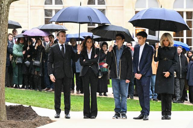 France's President Emmanuel Macron (L) stands next to a commemorative oak tree dedicated to Ilan Halimi, a 23-year-old French Jew who was tortured and murdered in 2006, as he is accompanied by Ilan's sister Anne-Laure Abitbol (2nd L), Ilan's nephews and wife of France's President Brigitte Macron (R) during a ceremony commemorating the 20th anniversary of his murder at The Elysee Presidential Palace in Paris on February 13, 2026. (Photo by Bertrand GUAY / POOL / AFP)