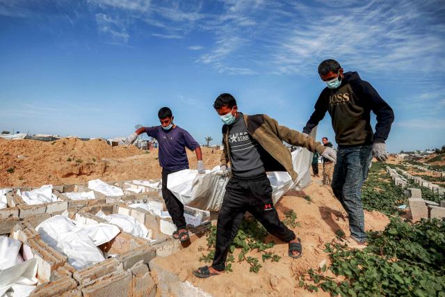 Men carry a body bag as they bury one of 53 unidentified bodies at a cemetery in Deir el-Balah in the central Gaza Strip on February 13, 2026. Since October 10, a fragile US-sponsored truce in Gaza has largely halted the fighting between Israeli forces and Hamas, but both sides have alleged frequent violations. (Photo by EYAD BABA / AFP)
