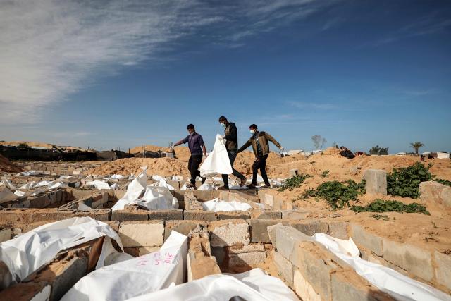 Men carry a body bag as they bury one of 53 unidentified bodies at a cemetery in Deir el-Balah in the central Gaza Strip on February 13, 2026. Since October 10, a fragile US-sponsored truce in Gaza has largely halted the fighting between Israeli forces and Hamas, but both sides have alleged frequent violations. (Photo by EYAD BABA / AFP)