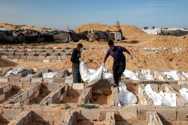 Men carry a body bag as they bury one of 53 unidentified bodies at a cemetery in Deir el-Balah in the central Gaza Strip on February 13, 2026. Since October 10, a fragile US-sponsored truce in Gaza has largely halted the fighting between Israeli forces and Hamas, but both sides have alleged frequent violations. (Photo by EYAD BABA / AFP)