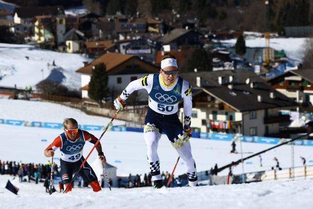 Armenia's Mikayel Mikayelyan (L) and Sweden's Gustaf Berglund compete during the men's 10km cross-country interval start free event of the Milano Cortina 2026 Winter Olympic Games at Tesero Cross-Country Skiing Stadium in Lago di Tesero (Val di Fiemme) on February 13, 2026. (Photo by Anne-Christine POUJOULAT / AFP)