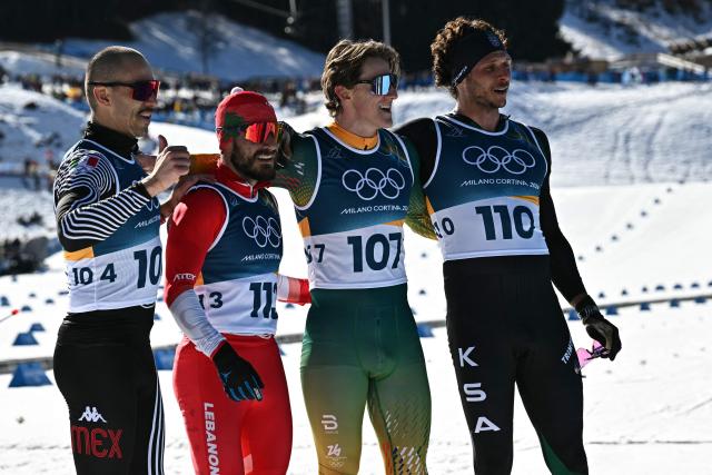 (fromL) Mexico's Allan Corona, Lebanon's Samer Tawk, South Africa's Matthew Smith and Saudi Arabia's Rakan Alireza pose after crossing the finish line during the men's 10km cross-country interval start free event of the Milano Cortina 2026 Winter Olympic Games at Tesero Cross-Country Skiing Stadium in Lago di Tesero (Val di Fiemme) on February 13, 2026. (Photo by Javier SORIANO / AFP)