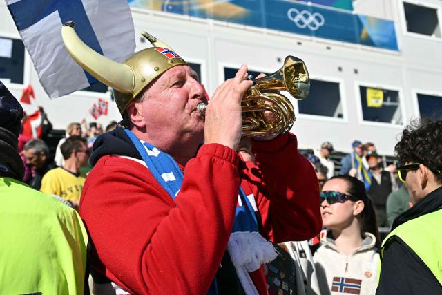 A Norway fan plays the trumpet after the men's 10km cross-country interval start free event of the Milano Cortina 2026 Winter Olympic Games at Tesero Cross-Country Skiing Stadium in Lago di Tesero (Val di Fiemme) on February 13, 2026. (Photo by Javier SORIANO / AFP)