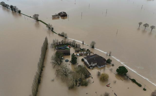This aerial photograph shows the overflowing Garonne river inundating a residential area in Tonneins, south-western France on February 13, 2026, after winds of Storm Nils swept across France. Storm Nils, which swept across France for two days, has claimed a second life according to the government in the south-west, where a red alert remains in place for flooding on the Garonne river. France's government spokesperson announced on the morning of February 13, 2026, on French TV channel TF1 the death of a man who was "on a ladder in his garden" in Tarn-et-Garonne. (Photo by Christophe ARCHAMBAULT / AFP)