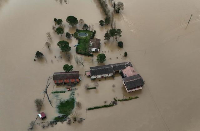 This aerial photograph shows the overflowing Garonne river inundating a residential area in Tonneins, south-western France on February 13, 2026, after winds of Storm Nils swept across France. Storm Nils, which swept across France for two days, has claimed a second life according to the government in the south-west, where a red alert remains in place for flooding on the Garonne river. France's government spokesperson announced on the morning of February 13, 2026, on French TV channel TF1 the death of a man who was "on a ladder in his garden" in Tarn-et-Garonne. (Photo by Christophe ARCHAMBAULT / AFP)
