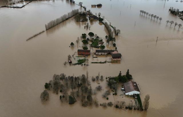 This aerial photograph shows the overflowing Garonne river inundating a residential area in Tonneins, south-western France on February 13, 2026, after winds of Storm Nils swept across France. Storm Nils, which swept across France for two days, has claimed a second life according to the government in the south-west, where a red alert remains in place for flooding on the Garonne river. France's government spokesperson announced on the morning of February 13, 2026, on French TV channel TF1 the death of a man who was "on a ladder in his garden" in Tarn-et-Garonne. (Photo by Christophe ARCHAMBAULT / AFP)