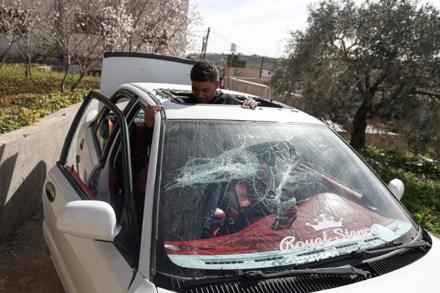 A Palestinian youth inspects one of several cars vandalised by Jewish settlers, who entered the Palestinian village of Telfit, south of the Israeli-occupied West Bank city of Nablus on February 13, 2026. The latest violence came days after Israel's security cabinet approved measures to tighten control over the West Bank, paving the way for further settlement expansion. Excluding Israeli-annexed east Jerusalem, more than 500,000 Israelis live in settlements and outposts across the West Bank, which are illegal under international law. (Photo by JAAFAR ASHTIYEH / AFP)