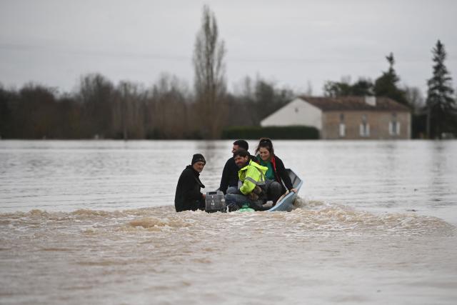 Local residents assist each other to evacuate the area by boat as the Garonne river overflows and inundates a residential area in Tonneins, south-western France on February 13, 2026, after winds of Storm Nils swept across France. Storm Nils, which swept across France for two days, has claimed a second life according to the government in the south-west, where a red alert remains in place for flooding on the Garonne river. France's government spokesperson announced on the morning of February 13, 2026, on French TV channel TF1 the death of a man who was "on a ladder in his garden" in Tarn-et-Garonne. (Photo by Christophe ARCHAMBAULT / AFP)