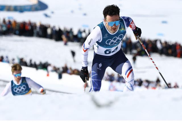 France's Jules Lapierre (R) competes during the men's 10km cross-country interval start free event of the Milano Cortina 2026 Winter Olympic Games at Tesero Cross-Country Skiing Stadium in Lago di Tesero (Val di Fiemme) on February 13, 2026. (Photo by Anne-Christine POUJOULAT / AFP)