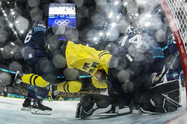 Sweden's #40 Elias Pettersson (C) falls as he vies with Finland's #56 Erik Haula (L) and Finland's #74 Juuse Saros (R)  during the men's preliminary round Group B Ice Hockey match between Finland and Sweden at the Milano Santagiulia Ice Hockey Arena during the Milano Cortina 2026 Winter Olympic Games in Milan, on February 13, 2026. (Photo by POOL / AFP)