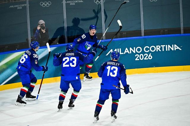 Italy's #10 Dustin James Gazley (C) celebrates with teammates after scoring his team second goal during the men's preliminary round Group B Ice Hockey match between Italy and Slovakia at the Milano Rho Ice Hockey Arena at the Milano Cortina 2026 Winter Olympic Games in Milan, on February 13, 2026. (Photo by JULIEN DE ROSA / AFP)