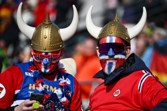 Norwegian supporters stand in the tribune during the men's biathlon 10km sprint event during the Milano Cortina 2026 Winter Olympic Games at the Anterselva Biathlon Arena (Sudtirol Arena) in Anterselva (Val Pusteria) on February 13, 2026. (Photo by Marco BERTORELLO / AFP)