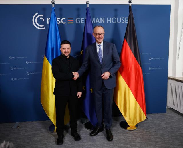 Ukrainian President Volodymyr Zelensky (L) and German Chancellor Friedrich Merz shake hands prior bilateral talks during the 62nd Munich Security Conference (MSC) on February 13, 2026 in Munich, southern Germany. Heads of state and government as well as foreign and defence ministers from all over the world are expected to attend the security policy talks from February 13 to 15, 2026. (Photo by Michaela STACHE / POOL / AFP)