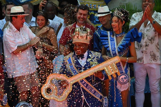 King Momo Cedric da Costa receives the key of the city from Rio de Janeiro Mayor Eduardo Paes (L) during the official Carnival opening ceremony in Rio de Janeiro, Brazil, on February 13, 2026. (Photo by Mauro PIMENTEL / AFP)