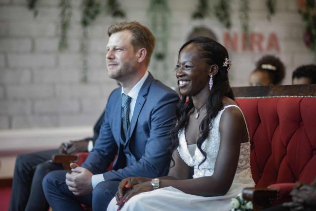 A couple reacts in front of the commissioner (Not seen) for Civil Registration at the National Identification and Registration Authority (NIRA) in Kampala, Uganda, on February 13, 2026. Fourteen couples, including Ugandans, Congolese, and Eritreans, participated in a special Valentine's Day event organized by NIRA, held a day early due to the agency's closure on Saturday. (Photo by BADRU KATUMBA / AFP)