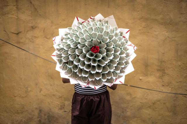 (FILES) Hannah James, 22, a supervisor at the Surprise World NG gift shop, poses for a photograph with a money bouquet at the Surprise World NG office in Ikeja in Lagos, on February 10, 2026. In the run-up to this year's Valentine's Day on February 14, 2026, romantics from Paris to Lagos and in the ongoing Olympic Games, are preparing to celebrate the Roman Saint Valentine whose feast day has since the Middle Ages been associated with courting couples. (Photo by OLYMPIA DE MAISMONT / AFP)