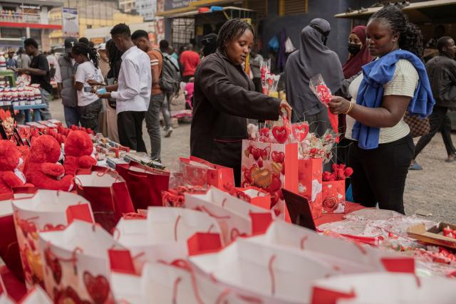 A pedestrian (R) buys from a vendor a Valentine Day gift  in downtown Nairobi, on February 13, 2026. (Photo by SIMON MAINA / AFP)