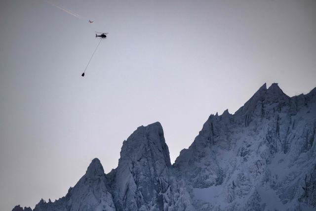 This photograph shows an helicopter, carrying a load with a sling, flying over the Massif du Mont-Blanc mountain range in the French Alps, near Chamonix on February 13, 2026. (Photo by OLIVIER CHASSIGNOLE / AFP)