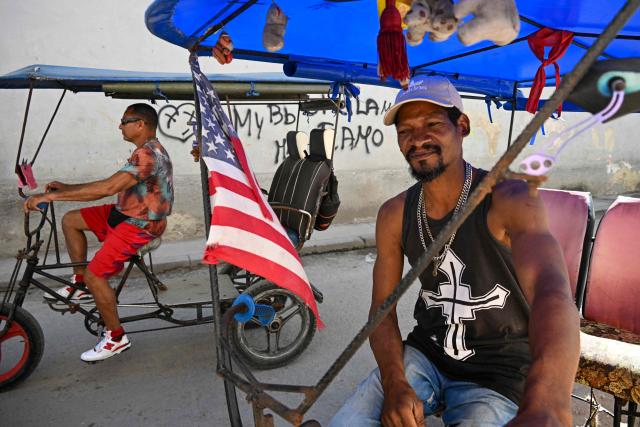 A tricycle taxi decorated with the US flagwaits for costumers in a street in Havana, on February 12, 2026. The fuel crisis in Cuba, and particularly in Havana, is forcing many workers who depend on daily mobility to abandon gasoline cars and turn to electric tricycles and bicycle taxis as more accessible alternatives. (Photo by YAMIL LAGE / AFP)