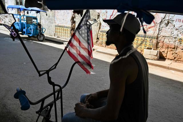 A tricycle taxi decorated with the US flagwaits for costumers in a street in Havana, on February 12, 2026. The fuel crisis in Cuba, and particularly in Havana, is forcing many workers who depend on daily mobility to abandon gasoline cars and turn to electric tricycles and bicycle taxis as more accessible alternatives. (Photo by YAMIL LAGE / AFP)
