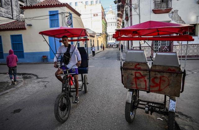 A pedicab rides along a street in Havana, Cuba on February 13, 2026. The fuel crisis in Cuba, and particularly in Havana, is forcing many workers who depend on daily mobility to abandon gasoline cars and turn to electric tricycles and bicycle taxis as more accessible alternatives. (Photo by YAMIL LAGE / AFP)