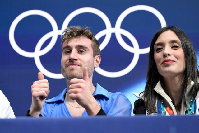 Italy's Matteo Rizzo (L) reacts in the kiss and cry area after competing in the figure skating men's singles free skating final during the Milano Cortina 2026 Winter Olympic Games at Milano Ice Skating Arena in Milan on February 13, 2026. (Photo by WANG Zhao / AFP)