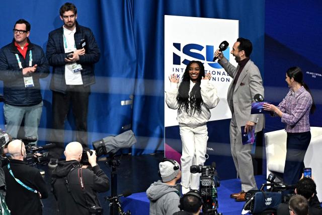 USA's athlete Simone Biles (3R) waves to spectators at Milano Ice Skating Arena during the figure skating men's singles free skating final at the Milano Cortina 2026 Winter Olympic Games, in Milan on February 13, 2026. (Photo by Gabriel BOUYS / AFP)