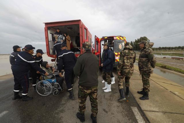 Members of the Royal Armed Forces (FAR), civil protection services and local authorities assist in evacuating people affected by the flooding in the Sidi Slimane region, in northwestern Morocco on February 13, 2026. In Morocco, agriculture is a major sector, accounting for 12% of GDP and around a third of jobs. In recent weeks, the North African country has experienced unprecedented rainfall which, according to the government, has caused ‘the flooding of 110,000 hectares’ in the regions of Larache. (Photo by Abdel Majid BZIOUAT / AFP)