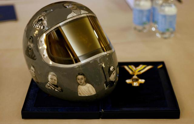 Ukrainian skeleton athlete Vladyslav Heraskevych's helmet is pictured next to a medal during a meeting with Heraskevych and Ukrainian President Volodymyr Zelensky in Munich, southern Germany, on the sidelines of the 62nd Munich Security Conference (MSC) on February 13, 2026. Heraskevych was barred from the Milan-Cortina Games after refusing to back down from wearing a helmet adorned with pictures of Ukrainian sportsmen and women killed since Russian invaded in 2022. (Photo by Alexandra BEIER / AFP)