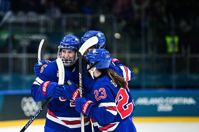 USA's defender #05 Megan Keller (L) celebrates with teammates after scoring her team first goal during the women's quarter final Ice Hockey match between USA and Italy at the Milano Rho Ice Hockey Arena at the Milano Cortina 2026 Winter Olympic Games in Milan, on February 13, 2026. (Photo by JULIEN DE ROSA / AFP)
