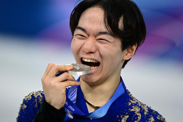 Silver medallist Japan's Yuma Kagiyama bites on his medal on the podium of the figure skating men's singles free skating final during the Milano Cortina 2026 Winter Olympic Games at Milano Ice Skating Arena in Milan on February 13, 2026. (Photo by Piero CRUCIATTI / AFP)