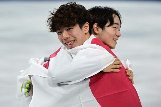 Silver medallist Japan's Yuma Kagiyama and bronze medallist Japan's Shun Sato hug each other following the victory ceremony of the figure skating men's singles free skating final during the Milano Cortina 2026 Winter Olympic Games at Milano Ice Skating Arena in Milan on February 13, 2026. (Photo by Piero CRUCIATTI / AFP)