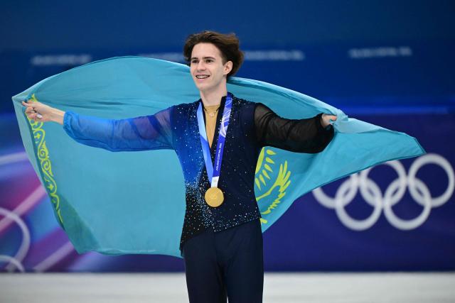 Gold medallist Kazakhstan's Mikhail Shaidorov poses with his country's flag following the victory ceremony of the figure skating men's singles free skating final during the Milano Cortina 2026 Winter Olympic Games at Milano Ice Skating Arena in Milan on February 13, 2026. (Photo by Piero CRUCIATTI / AFP)