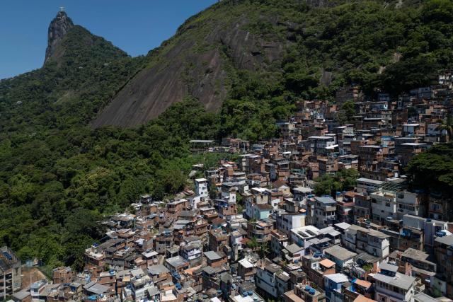 This aerial view shows the Santa Marta favela (R) and the Christ the Redeemer statue on the top of Corcovado mountain (L) in the south zone of Rio de Janeiro, Brazil, on February 13, 2026. The Santa Marta favela, located on Dona Marta Hill between Botafogo and Laranjeiras in Rio de Janeiro's South Zone, is a vibrant community of roughly 3,9006,000 residents. It is a popular, generally safe tourist destination famous for its steep terrain, colorful houses, and the Michael Jackson statue marking where his 1995 music video was filmed. (Photo by MAURO PIMENTEL / AFP)