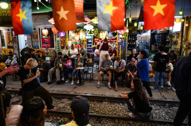 Tourists take photo along the railway track on the popular train street in Hanoi on February 13, 2026. (Photo by Amaury PAUL / AFP)