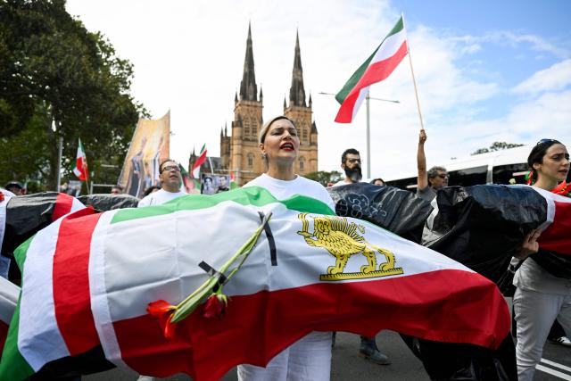 Members of the Iranian community carry mock coffins as they march during a rally in Sydney on February 14, 2026, calling for stronger international action and urging the United States to intervene against the current Iranian regime. (Photo by Saeed KHAN / AFP)