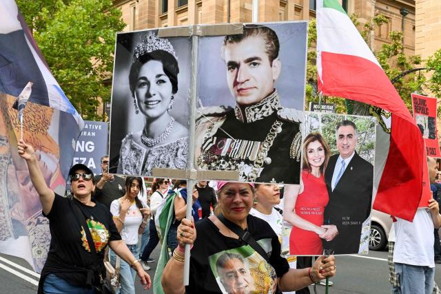 A member of the Iranian community carries a poster of last Shah of Iran Mohammad Reza Pahlavi during a rally in Sydney on February 14, 2026, calling for stronger international action and urging the United States to intervene against the current Iranian regime. (Photo by Saeed KHAN / AFP)