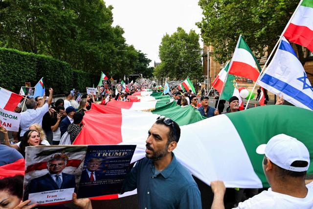 Members of the Iranian community carries flags and placards during a rally in Sydney on February 14, 2026, calling for stronger international action and urging the United States to intervene against the current Iranian regime. (Photo by Saeed KHAN / AFP)