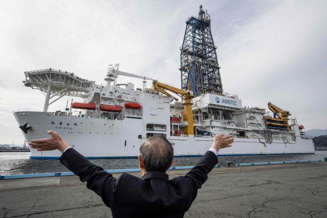 A man waves to Japan's deep-sea drilling vessel Chikyu as it returns to Shimizu port in Shimizu, Shizuoka prefecture on February 14, 2026. (Photo by Yuichi YAMAZAKI / AFP)