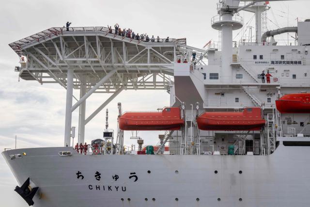 Crew members wave to watching public from aboard Japan's deep-sea drilling vessel Chikyu as it returns to Shimizu port in Shimizu, Shizuoka prefecture on February 14, 2026. (Photo by Yuichi YAMAZAKI / AFP)