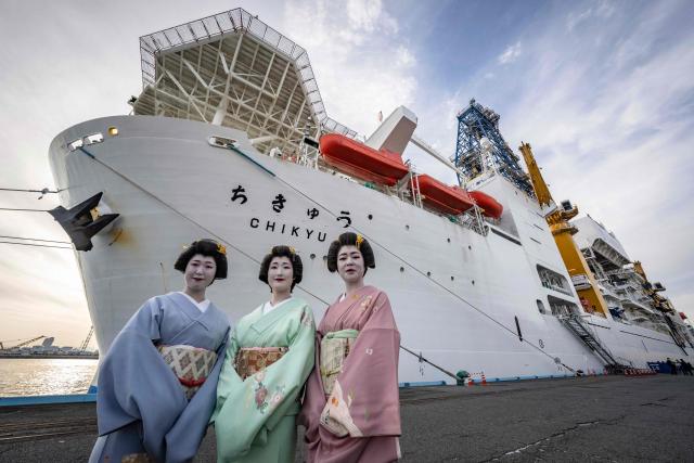 Local geishas pose in front of Japan's deep-sea drilling vessel Chikyu as it returns to Shimizu port in Shimizu, Shizuoka prefecture on February 14, 2026. (Photo by Yuichi YAMAZAKI / AFP)