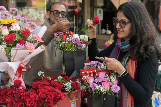 A woman buys roses from a flower shop along a street on Valentine's Day in Amritsar on February 14, 2026. (Photo by Narinder NANU / AFP)