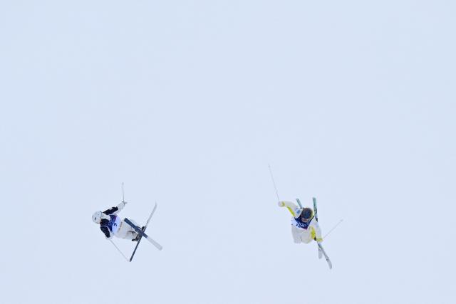 Japan's Hinako Tomitaka (L) and Kazakhstan's Yuliya Galysheva (R) compete in the freestyle skiing women's dual moguls last 16 during the Milano Cortina 2026 Winter Olympic Games at Livigno Aerials & Moguls Park, in Livigno (Valtellina), on February 14, 2026. (Photo by Kirill KUDRYAVTSEV / AFP)