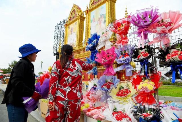 A woman buys flowers in front of a portrait of King Norodom Sihamoni on Valentine's Day in Phnom Penh on February 14, 2026. (Photo by TANG CHHIN Sothy / AFP)