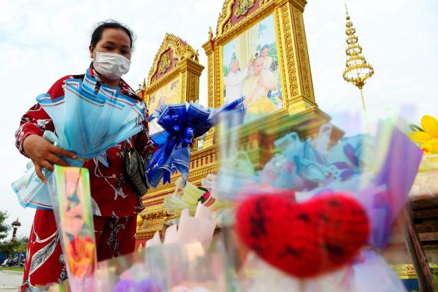 A woman buys flowers in front of a portrait of King Norodom Sihamoni on Valentine's Day in Phnom Penh on February 14, 2026. (Photo by TANG CHHIN Sothy / AFP)
