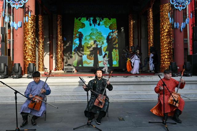 Men perform music on a street in Beijing on February 14, 2026, ahead of the Lunar New Year of the Horse. (Photo by ADEK BERRY / AFP)